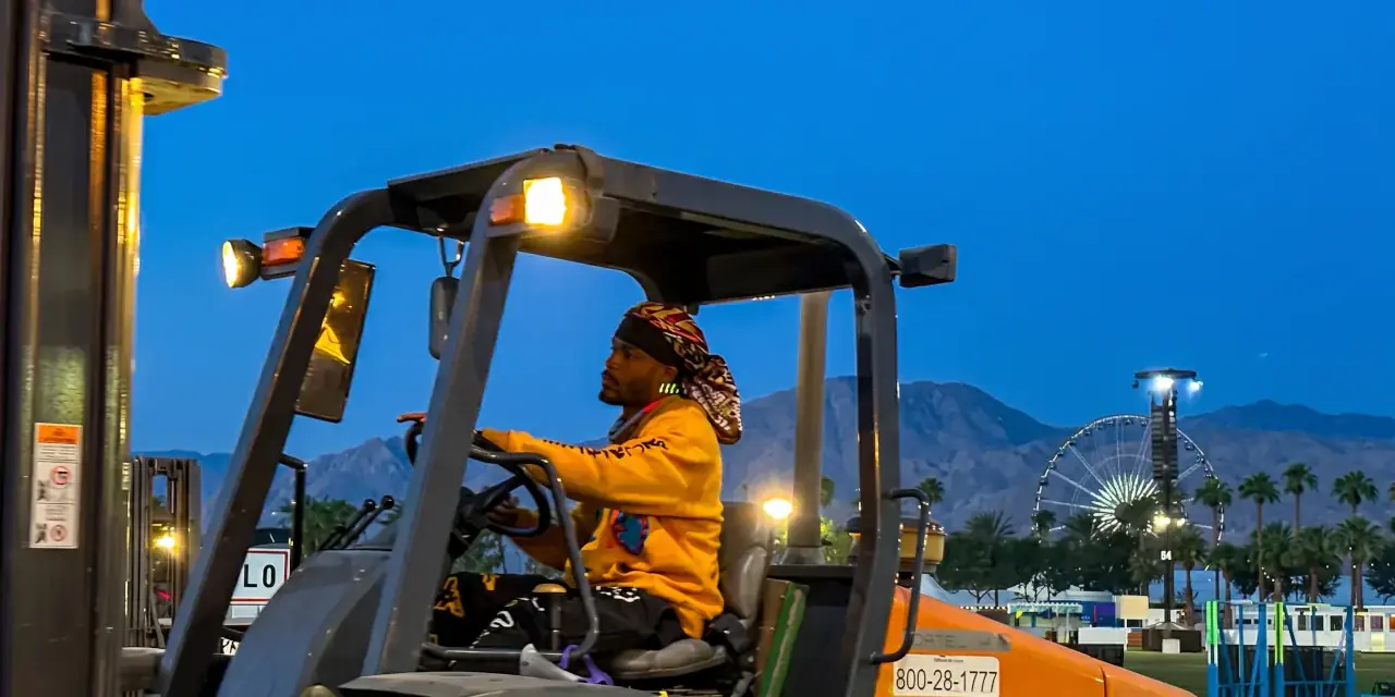 Forklift operator and gear handler moving equipment in a production warehouse